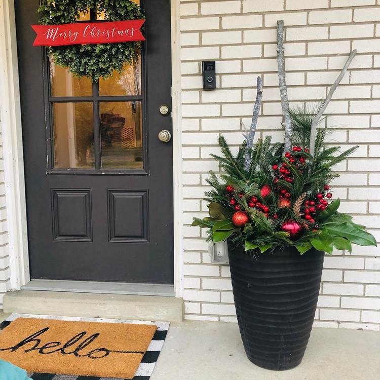 Vianočné aranžmán s červenými akcentmi na prahu