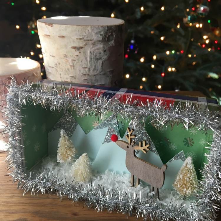 Drotárska zimná krajina v kartónovej škatuli s deťmi a so striebornou girlandou