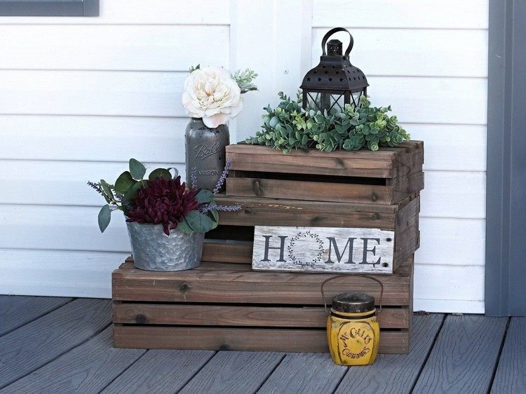 Dekorácia v januári pri vchode do domu s drevenými debničkami a kvetmi