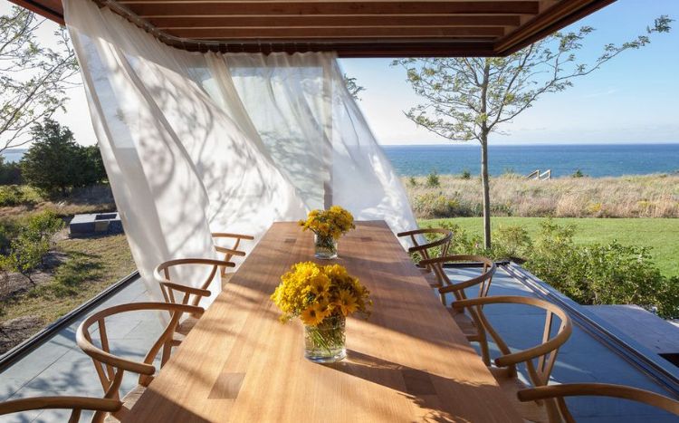 stolička na kosenie kostí hans wegner carl hansen záhrada vonkajšia časť pergola výhľad na more žlté kvety vázy