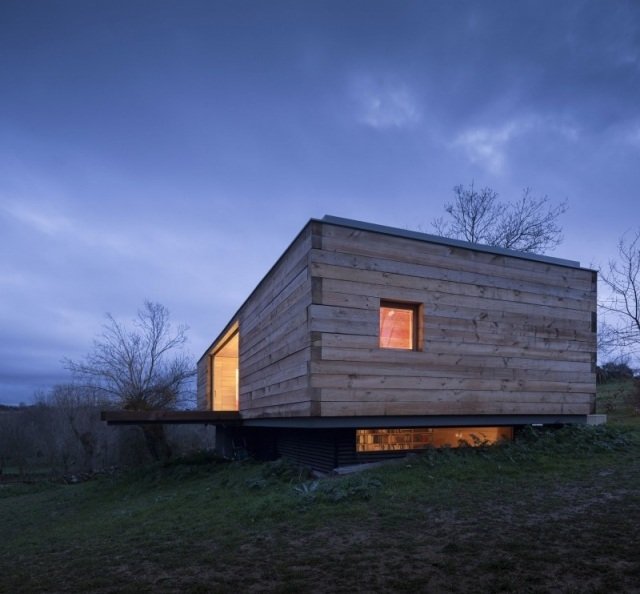 moderný obytný pavilón z dreva a sklenenej plochej strechy vo svahu