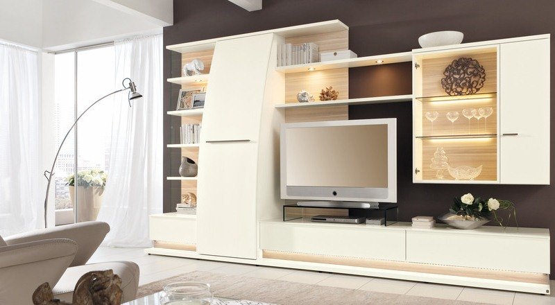 Nástenná jednotka úplne v bielej farbe so sklenenými vitrínami s osvetlením Nápady na obývaciu stenu Biele vysoko lesklé LED osvetlenie zariadilo obývaciu izbu