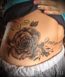 Fekete rózsa tetoválás feliratokkal a gyomor alján