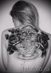 Fekete rózsa tetoválás a lány hátán - rajz nagy koponyával