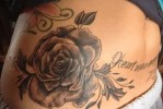 Fekete rózsa tetoválás feliratokkal a gyomor alján