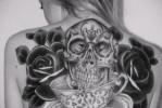 Fekete rózsa tetoválás a lány hátán - rajz nagy koponyával