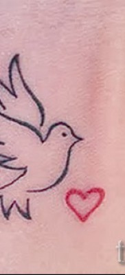 Снимка на гълъб и татуировка на сърце на китката на момичето