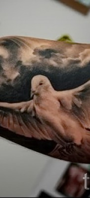 Снимка на татуировка на бял гълъб в полет - небе в облаци - татуировка на ръка за човек