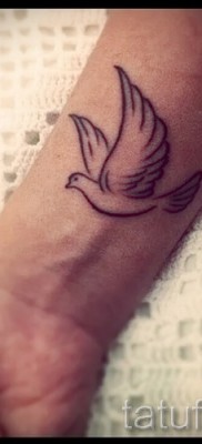 Снимка на татуировка на гълъб - работа с линии на китката за момиче