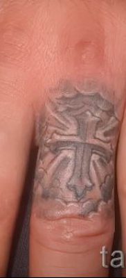 Egy fotó egy szokatlan kész tetoválásról egy ujjal, egy kereszttel a saját rajz kiválasztásához és rajzolásához - egy lehetőség