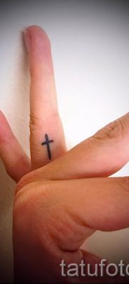 Egy fotó egy érdekes tetoválásról az ujján, amelynek keresztje már fel van helyezve a testre a saját vázlat kiválasztásához és rajzolásához - példa