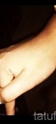 Egy fotó egy menő tetoválásról, amelyet már a testre alkalmaztak egy ujjal, egy kereszttel a saját rajz kiválasztásához és létrehozásához - egy ötlet