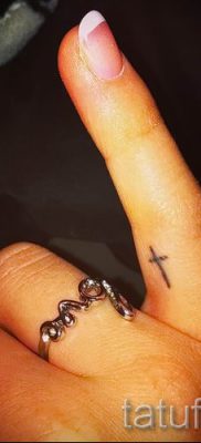 Fotó egy érdekes meglévő tetoválásról egy ujjal, egy kereszttel, hogy kiválassza és rajzoljon saját vázlatot - egy példa