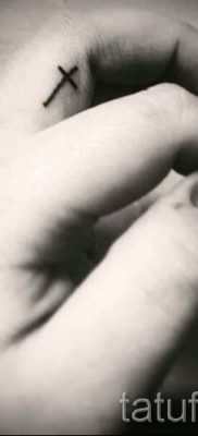 Egy fénykép egy méltó kész tetoválásról egy ujjal, egy kereszttel a saját rajz kiválasztásához és rajzolásához - egy lehetőség