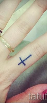 Fotó egy hűvös kész tetoválásról egy ujjal, egy kereszttel a saját vázlat kiválasztásához és létrehozásához - példa