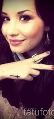 Egy fotó egy szokatlan meglévő tetoválásról egy ujjal, egy kereszttel a saját rajz kiválasztásához és létrehozásához - példa