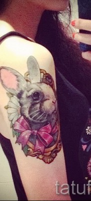 Снимка на заешка татуировка с розов лък на рамото на момиче