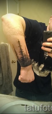 Erdei tetoválás egy férfi jobb kezén, csuklóján karkötővel