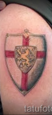 Fénykép egy pajzs tetoválásáról, kereszt és oroszlán