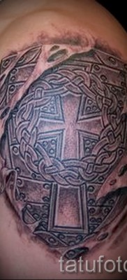 Fénykép egy pajzs tetoválásáról egy kereszttel - egy férfi vállára felhelyezve