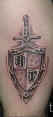 Fotó tetováló pajzsról és kardról betűkkel