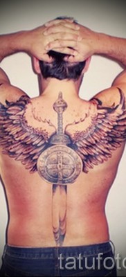 Fotó egy pajzs tetoválásáról és egy kard szárnyakkal az ember hátán
