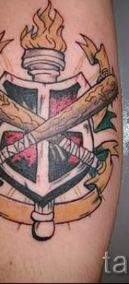 Fotó egy pajzs tetoválásról - egy fáklya és két bit