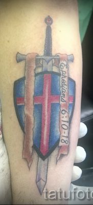 A pajzs és a kard hűvös tetoválásának változata az anyaghoz a karddal ellátott pajzs tetoválásának jelentéséről
