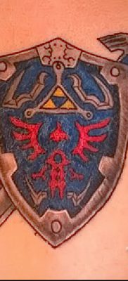 Fotó a pajzs és a kard sikeres tetoválásáról az anyaghoz, a karddal ellátott tetoválópajzs jelentéséről