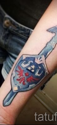 Fotó a pajzs és a kard sikeres tetoválásáról a karddal ellátott pajzs tetoválásának történetéről