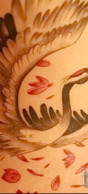 Пример за снимка на татуировка на кран - версия с цветни венчелистчета - татуировка в долната част на гърба на момичето