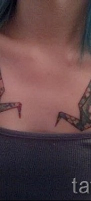 Пример за снимка на татуировка с кран - кранове от хартия на гърдите на младо красиво момиче