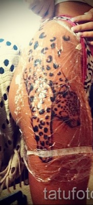 Fotó egy leopárd tetoválásról - friss tetoválás egy lány alján és combján