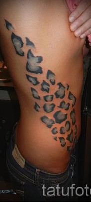 Fotó egy leopárd tetoválásról - egy színes csík foltokkal az oldalán és egy lány bordáin