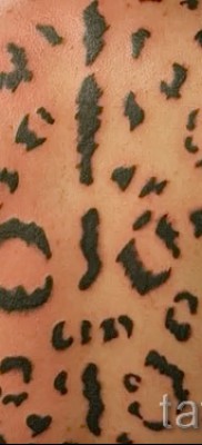 Fotó egy leopárd tetoválásról - színezés foltokkal az ember hátán