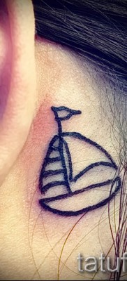 Fotó egy vitorlás tetoválásról egy lány füle mögött