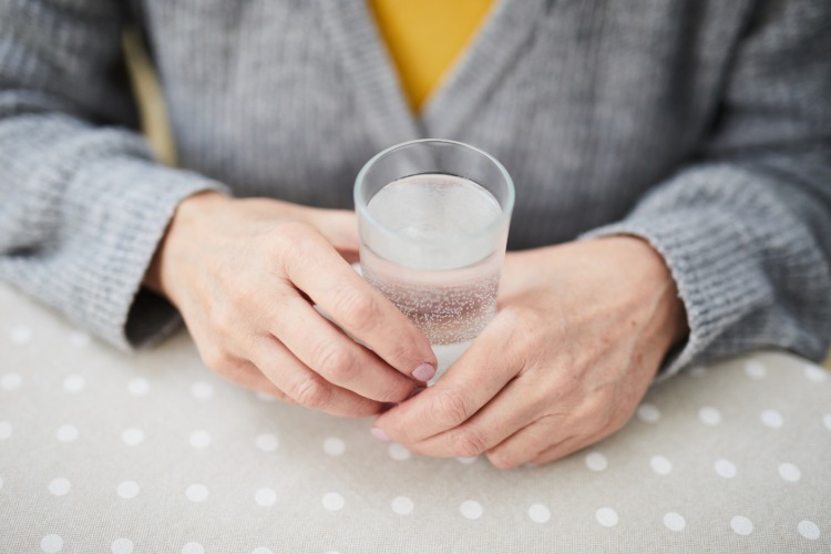 drží v rukách sýtený nápoj